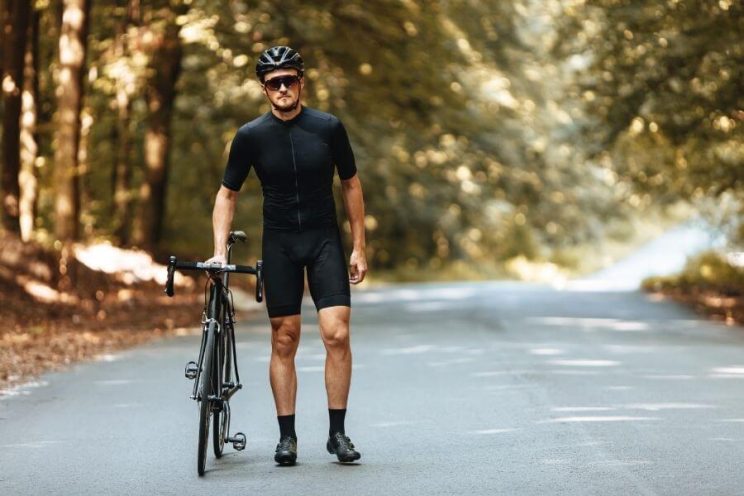 Cycliste debout à côté de son vélo de route et lunettes en été